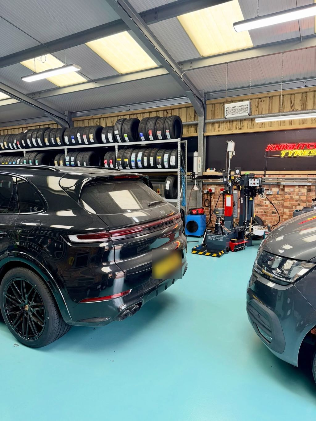 A black Porsche in the workshop bay at Knightcott, tyre racks and the tyre changer behind