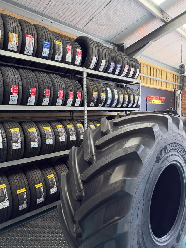 Racks of new car tyres with a large agricultural tyre standing in front of them