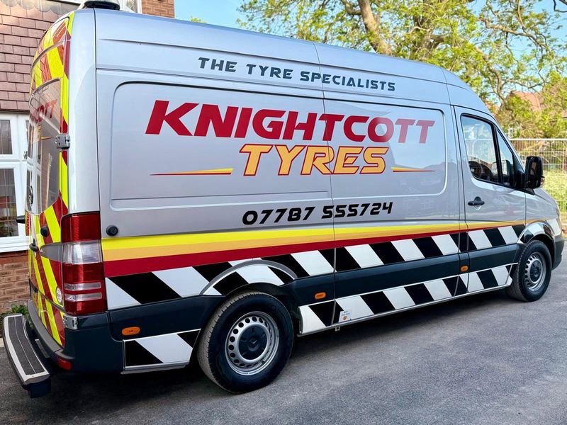 The silver Knightcott Tyres van side-on, the logo, livery and phone number on its side