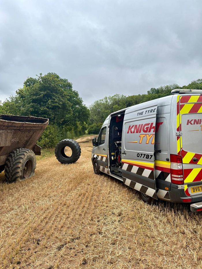 The silver Knightcott van in a stubble field, a large tyre stood up beside a trailer